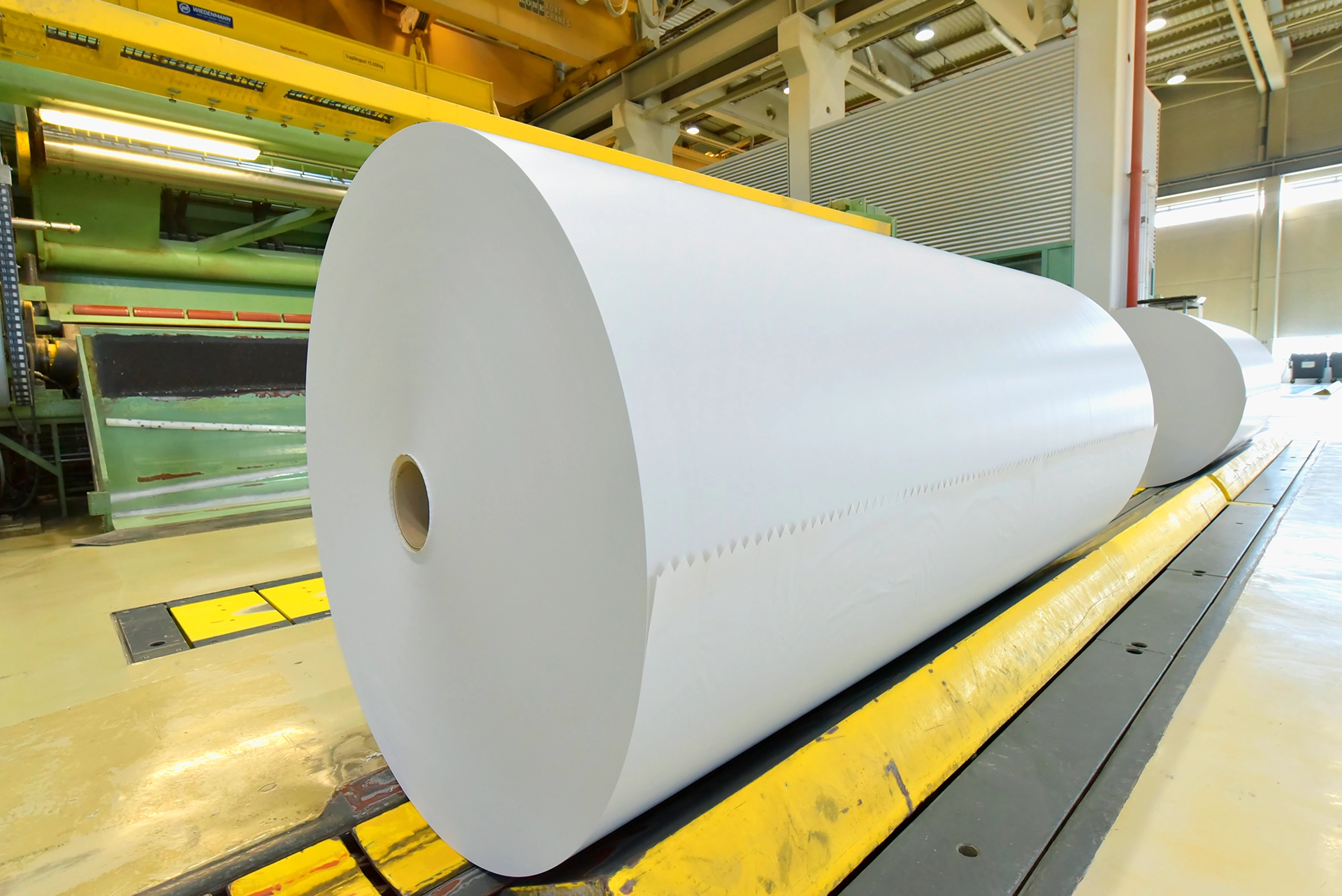 Large paper rolls moving through an industrial paper production facility